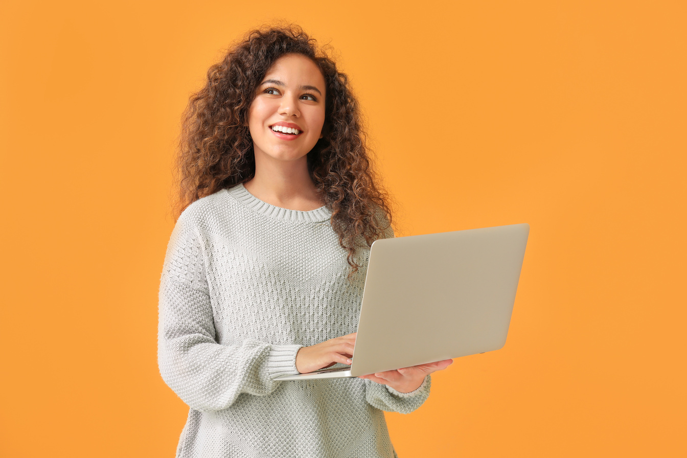Young African-American Woman with Laptop on Color Background